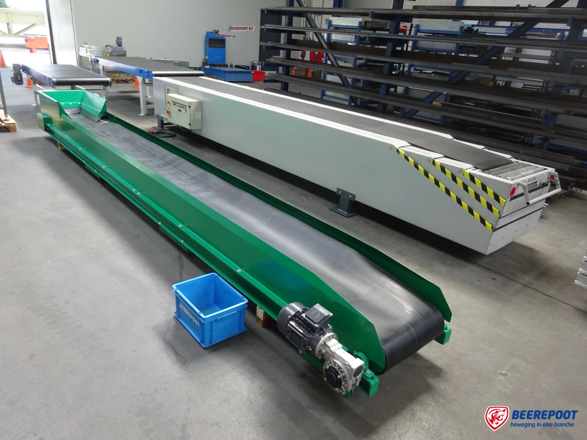Je ziet een groene trogband met daarvoor een blauw Beerepoot kratje. Erachter staat een lichtgrijze trogband. Op de achtergrond staat een rek met materialen. De foto is gemaakt in de werkplaats van Beerepoot.